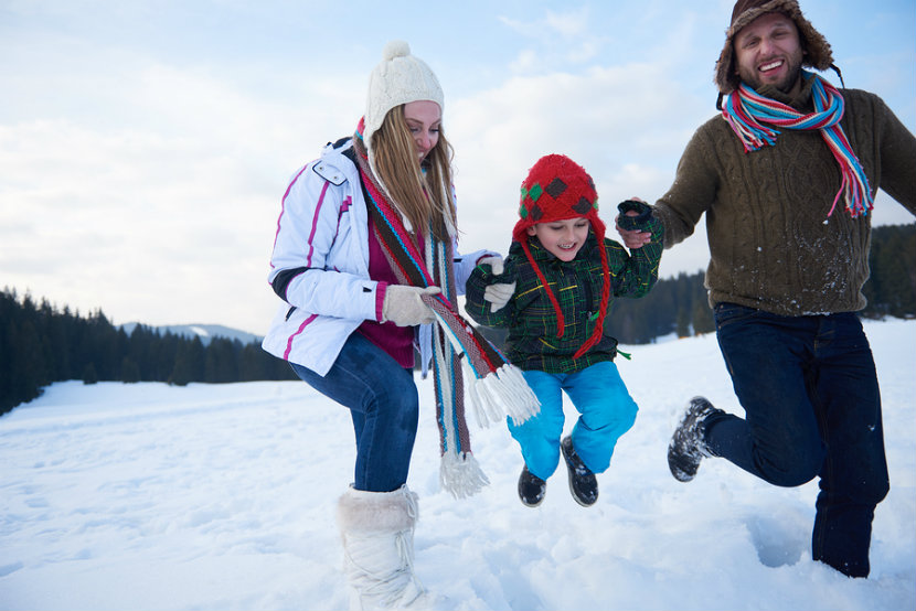 a mom and dad with their son dressed for winter in hats, boots, jacket