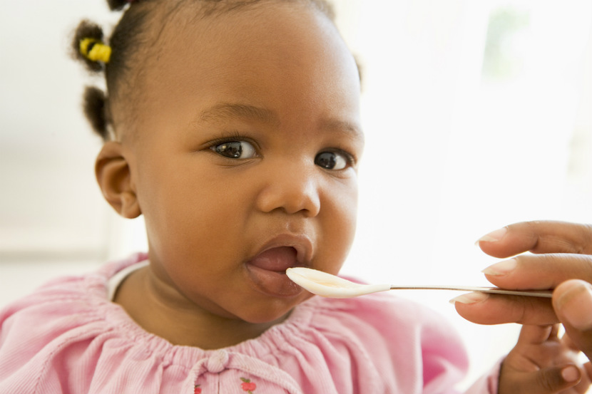 baby girl being fed solid food