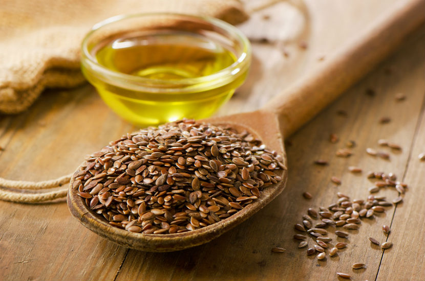 a bowl of linseed oil and a wooden spoon filled with flax seeds