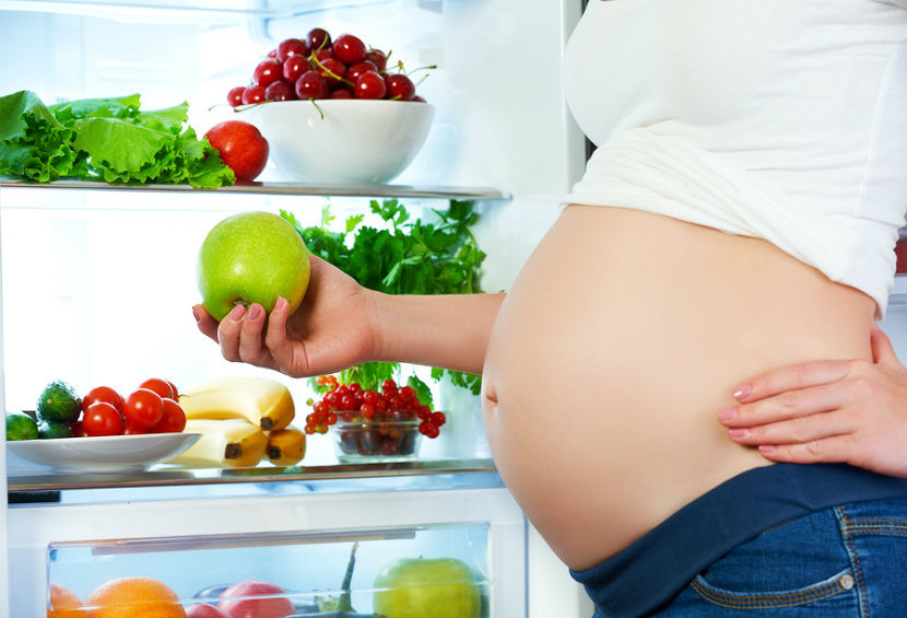 woman opening fridge door to get some fruit and vegetables