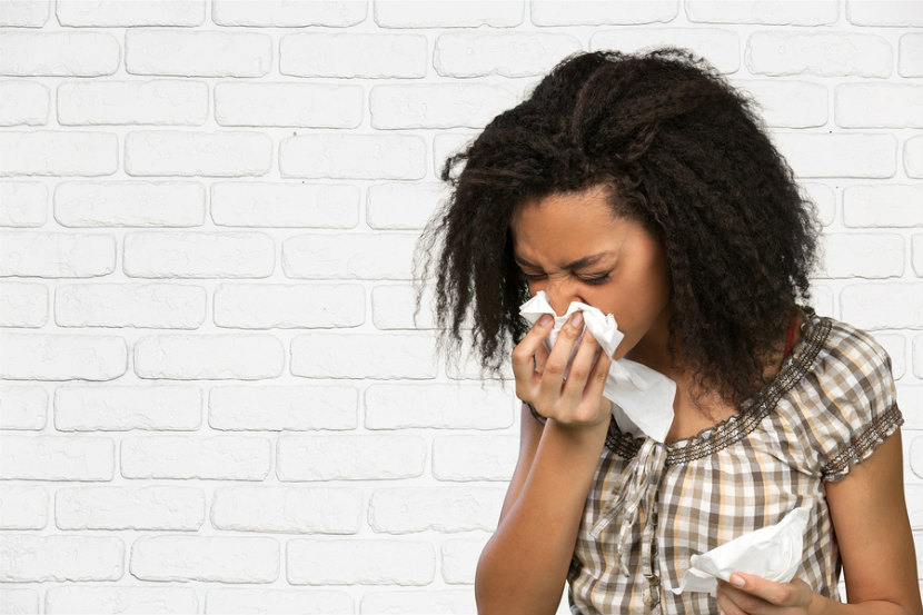 woman sneezing into a tissue