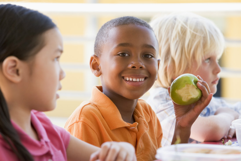 happy children sitting at a lunch table at school eating