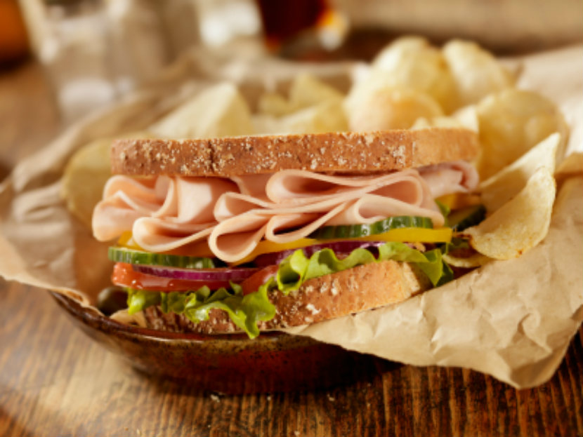 Turkey sandwich with cucumbers, lettuces, tomato and onion