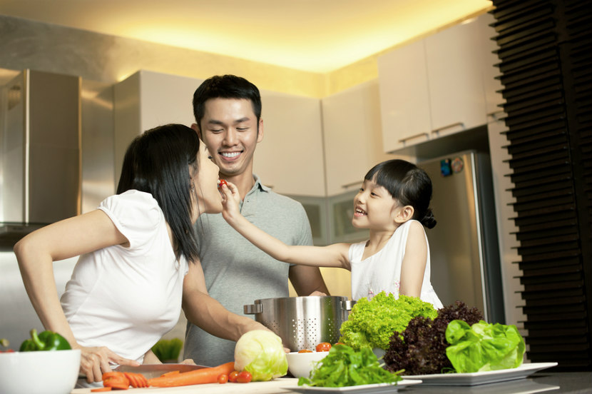 daughter feeding her mother a cherry tomato with father looking on