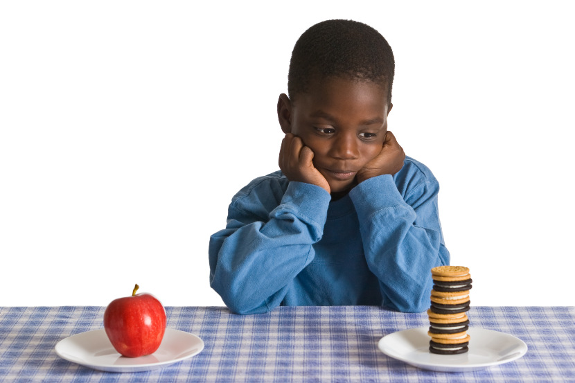 young boy choosing between an apple and dessert