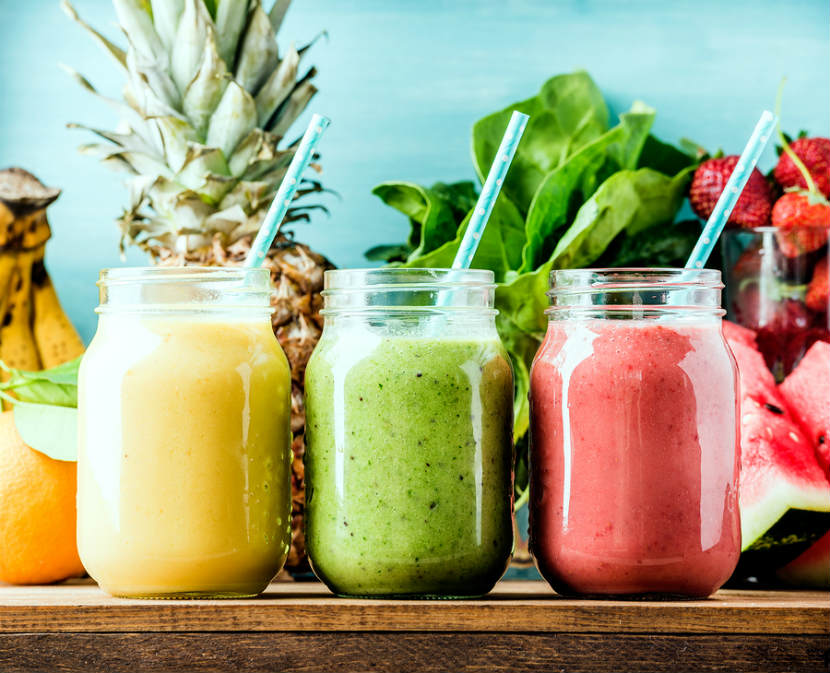 3 fruit smoothies in glass jars with a straw