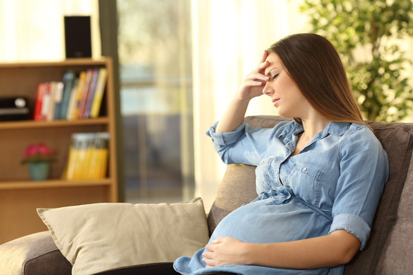 pregnant woman holding her head in pain