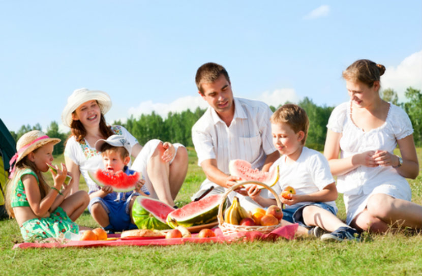 family on a picnic eating watermelon, 2 parents and 2 kids